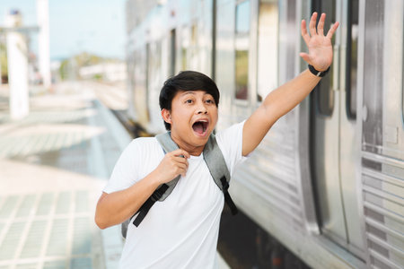 Young asian man with backpack running to catch the trainの写真素材