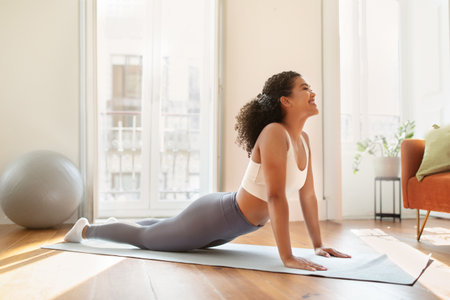 Young lady doing upward facing dog pose practicing yoga indoors