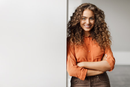 Confident businesswoman with arms crossed near blank boardの写真素材