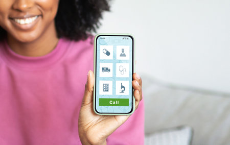 Smiling black woman demonstrating healthcare app opened on her smartphoneの写真素材