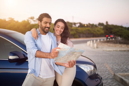 Young Arab couple planning road trip with map by car, free space