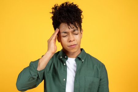 Unhappy millennial black man touching his headの写真素材