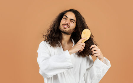 young man combs through curly hair suffering from pain, studioの写真素材