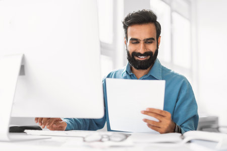 Content indian professional reviewing document at computer deskの写真素材