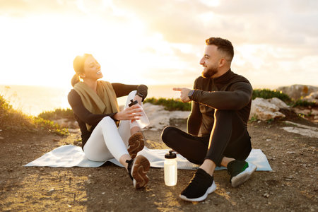 Laughing couple resting after workout with sea at sunsetの写真素材