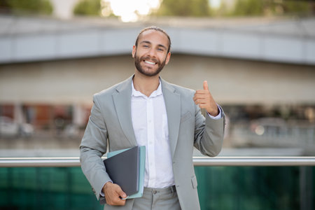 Optimistic young businessman giving thumb up while posing outdoorsの写真素材
