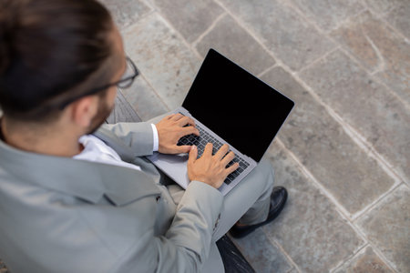 Overhead shot of focused businessman in suit typing on blank laptopの写真素材