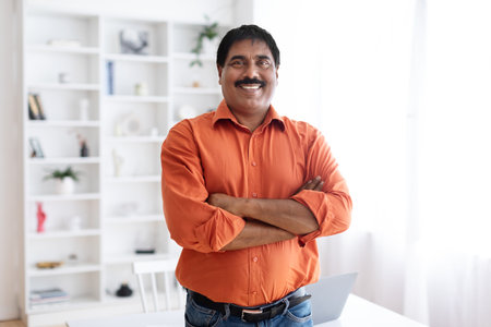 Handsome cheerful mature indian man posing at home officeの写真素材