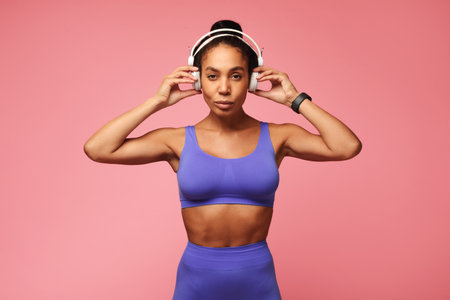 Athletic African American sportswoman in gym outfit wearing headphones, studioの写真素材