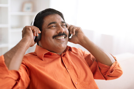 Closeup of middle aged indian man using wireless headphonesの写真素材