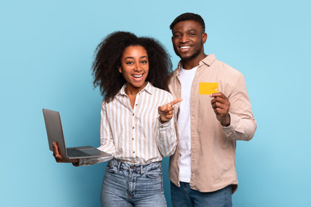 Cheerful african american couple with laptop and credit cardの写真素材