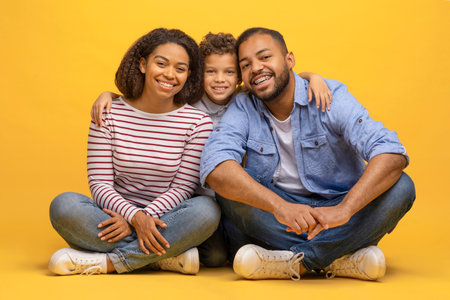 Happy african american family of three sitting on floor and embracingの写真素材