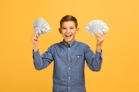 Excited teen boy holding dollar cash in both handsの写真素材