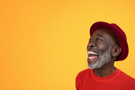Joyous senior Black man with a white beard, looking up and laughing in delightの写真素材