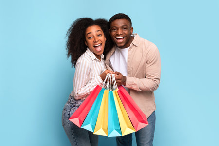 Joyful african american couple with colorful shopping bagsの写真素材