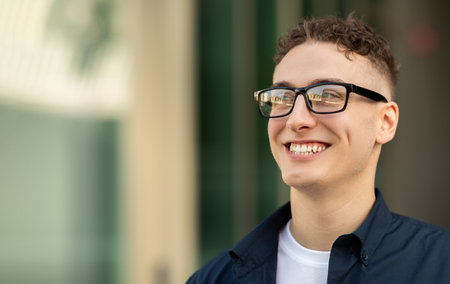 A smiling young man wearing glasses, a navy blue shirt, and a white t-shirtの写真素材