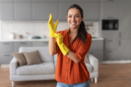 Smiling woman putting on yellow gloves for housework
