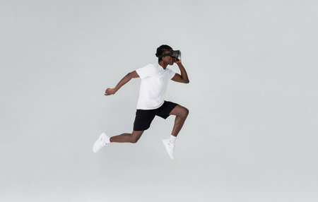 In motion shot of black man wearing vr headset running in studioの写真素材