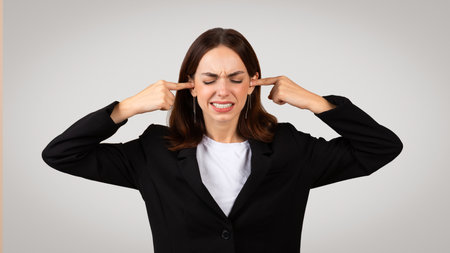 Sad tired young European woman in suit closed ears with hands, closed eyesの写真素材