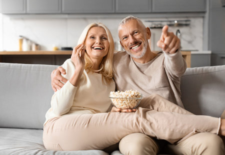 Happy senior couple watching TV together at homeの写真素材