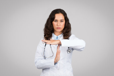 Doctor making timeout sign with serious faceの写真素材