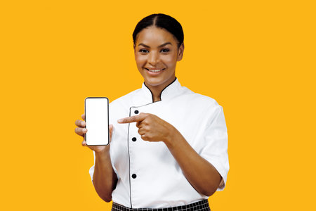 Cooking App. Black Female Chef Pointing At Blank Smartphone In Her Handの写真素材