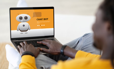 Over shoulder view african american man using chatbot on computerの写真素材