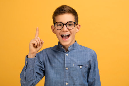 Enthusiastic teen boy wearing glasses pointing upwards with finger