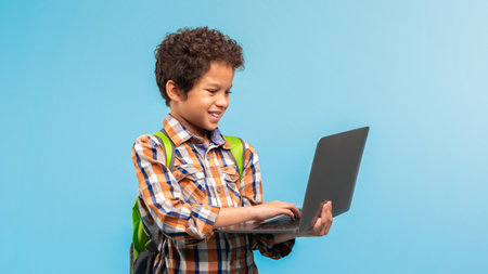 Boy with laptop and backpack, engaging with technologyの写真素材