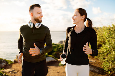 Jogging couple chatting on sunny coastal pathの写真素材