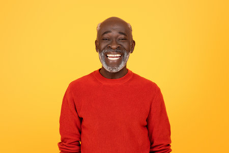 Radiant senior Black man with a white beard, sporting a red sweater and a beaming smileの写真素材