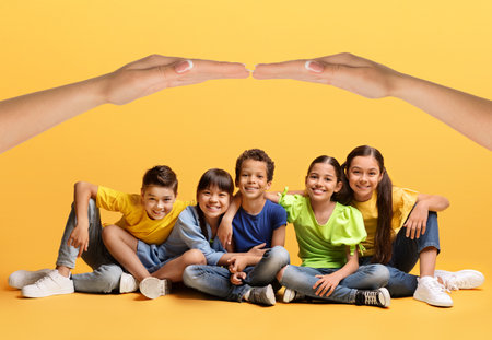 Happy multiethnic kids sitting on floor under hands roofの写真素材