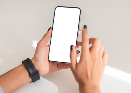 Close-up of hands holding a smartphone with a blank screen, showcasing a smartwatchの写真素材
