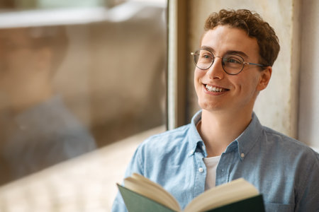 Glad calm handsome european young man student in glasses read book, enjoy peaceの写真素材