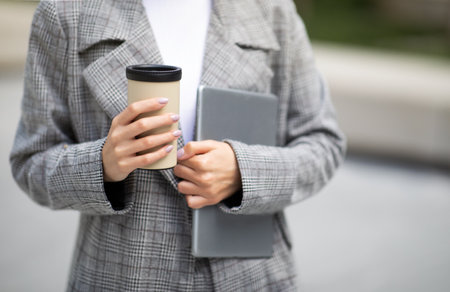 Cropped Shot Of Lady Holding Tablet And Coffee Cup Outsideの写真素材