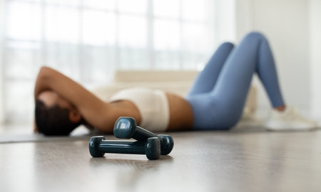 Tired black woman resting on a yoga mat after a strenuous workout session at homeの写真素材