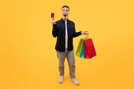 Emotional guy enjoying sale season, showing credit card and purchases