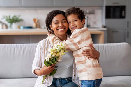 Smiling black mother receiving bouquet of flowers from her little son,の写真素材