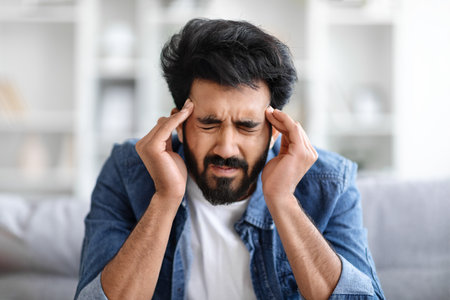 Distressed indian man pressing temples, showing signs of severe headache or stressの写真素材