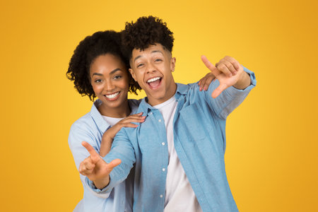 Glad inspired young african american guy and woman in casual make frame sign with handsの写真素材