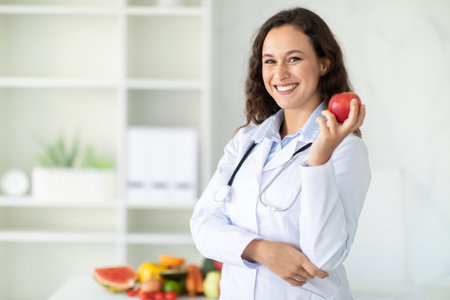 Portrait of smiling brunette woman working at clinic, holding appleの写真素材