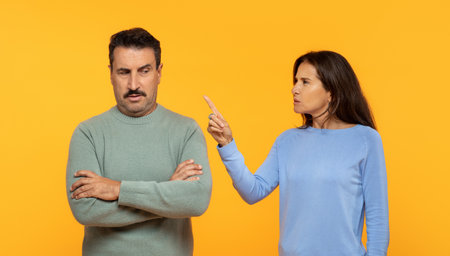 Angry european senior woman appears to be scolding a man who listens with a skeptical expressionの写真素材