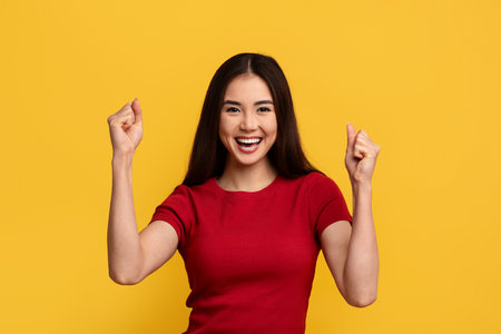 Excited young asian woman clenching fists and smilingの写真素材