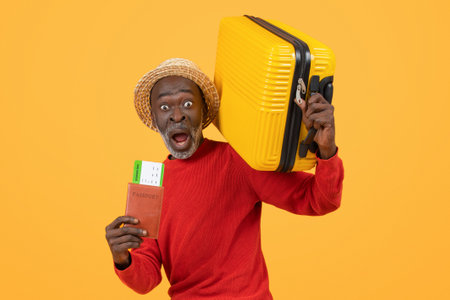 Startled senior African American man in a straw hat and red sweater holding a passportの写真素材
