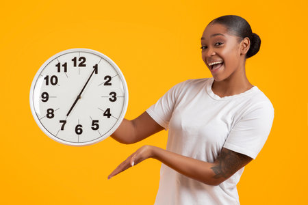 Positive Young Black Lady Showing Round Clock To Camera, Studio