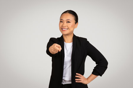 Engaging Asian businesswoman pointing directly at the camera with a confident smileの写真素材