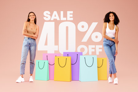 Two Stylish Young Women Advertising Sale Over Beige Studio Background