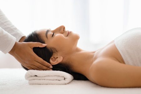 Masseuse making relaxing head massage for young beautiful indian ladyの写真素材