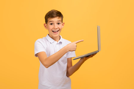 Online Education Concept. Happy teen boy pointing at laptop in his handの写真素材