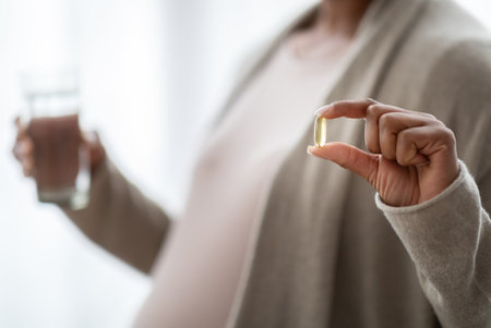 Cropped healthy young pregnant woman holding pill glass of waterの写真素材